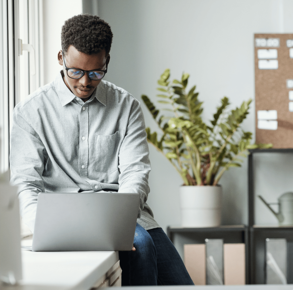 Man working on laptop with fake plant behind them