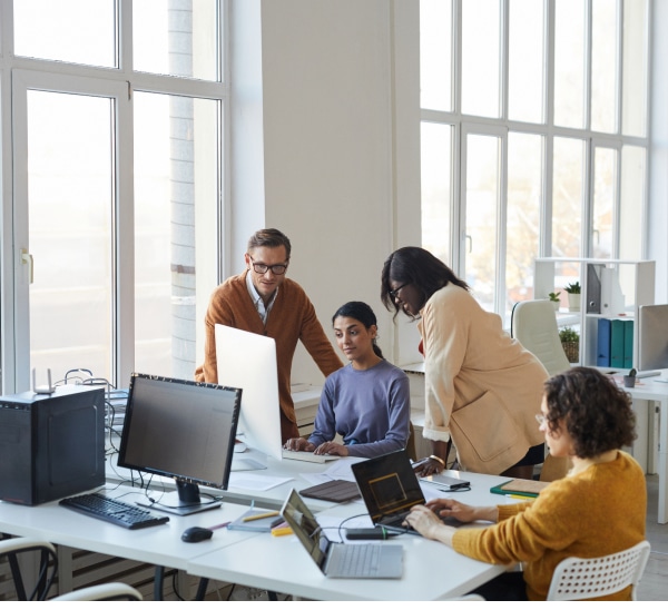 4 colleagues look at a large monitor together