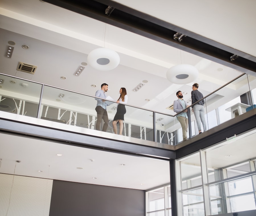 Colleagues chatting near a class railing in an office